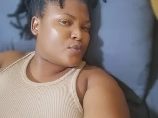 CandyYyumsAreolax wears a beige ribbed tank top while laying back against a blue pillow.