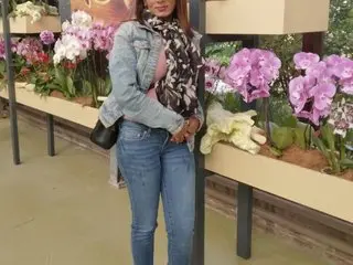 Candypussy333 poses in a light denim jacket and blue jeans, showing her long dark hair and smiling in an indoor setting.
