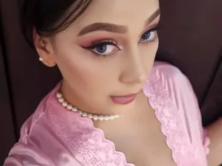 CandyyKissx poses in a pink lace top, showing her face, dark hair, and light pink makeup.