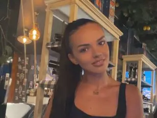 CarolinaPetra poses with long dark hair, wearing a black tank top, looking at the camera in an outdoor setting.