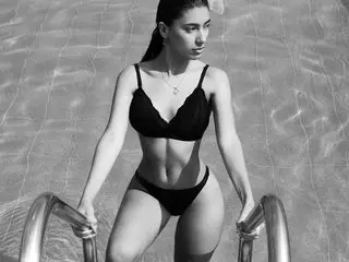 Cassey_Dager poses in a black bikini top and bottom while standing in shallow, rippling water.