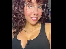 CassidyNicole poses with her long brown hair down, wearing a black tank top that shows off her cleavage and shoulders.