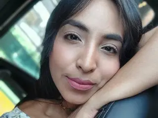 Catalina_99 poses with her hand against her face, showing her long dark hair and a close-up view of her face and neck.