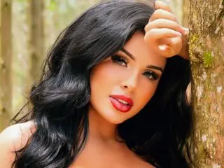 ChanelBrandd poses with her long black hair flowing over her shoulders, looking directly at the camera with red lipstick.