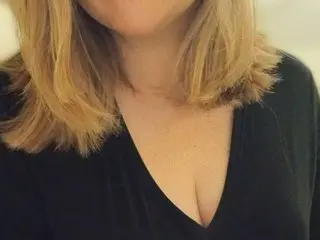 CharlotteBelleX shows her blonde hair and cleavage while wearing a black v-neck top.