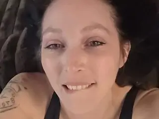 ChloeBenette smiles while lying down, showing her face and shoulders, wearing a black tank top top with her hair pulled back.