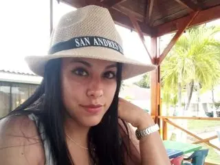 ChloeDivine111 wearing a white San Andres hat and a necklace while posing outdoors under a wooden gazebo.