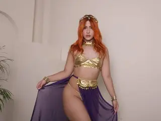 Woman in gold goddess costume and purple skirt posing in a bright indoor setting.