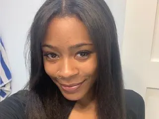 Cocoasuave smiles while looking at the camera, showing her long dark hair and black top in a close-up headshot.