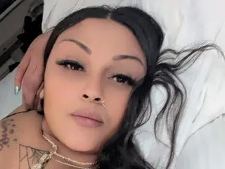 CreamyMacn poses with her long dark hair spread out, wearing a gold chain necklace and showing her nose ring.