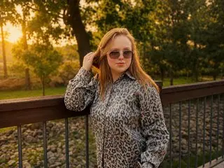 Blonde woman in leopard print shirt and sunglasses posing on a wooden deck during a golden hour sunset.
