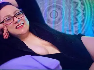 Smiling woman in black loungewear relaxing in a room with colorful mandala decor and moody lighting.