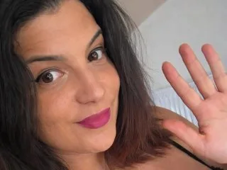 CurvyAna699 smiles at the camera while waving her hand in a close-up selfie.