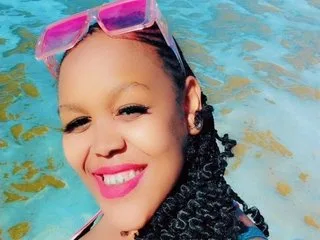 CurvyAuroraxx smiles in pink sunglasses while relaxing in a bright blue swimming pool.