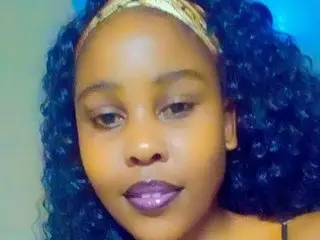 CurvyBootiliscious88 poses with her dark curly hair pulled back by a gold headband, looking directly at the camera.