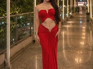 Cuteshristi stands on a balcony at night wearing a red strapless crop top and a matching long red skirt.