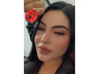 DalilaZaens poses close-up, showing her face, dark hair, and lips while looking directly into the camera.