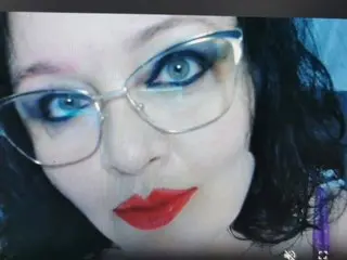 DangerousCurves poses close-up with dark hair and bright red lipstick, looking directly into the camera with blue eyes.