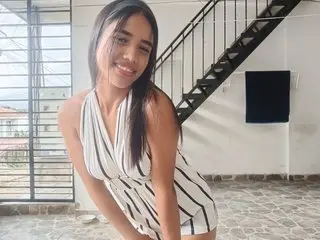 Danna_liz smiles while wearing a white striped sundress, posing outdoors near a black metal staircase.