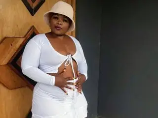 DarkEngelAss94 poses in a white crop top and matching skirt, showing off her cleavage and midriff against a dark background.