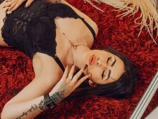 DeemiiMoore poses with her long dark hair spread out, wearing a black lace bodysuit that shows her cleavage and shoulders.