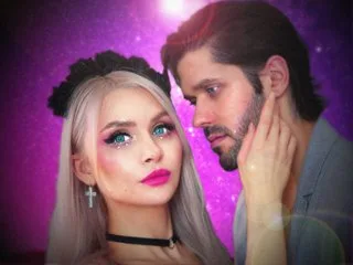 DenLina with long silver hair and a black headband poses next to a man against a purple sparkly background.