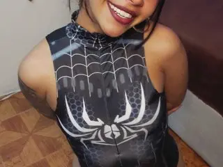 Smiling woman in a black Spider-Man cosplay bodysuit posing indoors with a joyful mood.