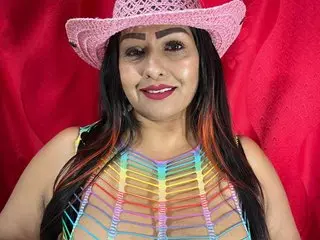 Smiling woman in a pink cowboy hat and colorful crochet top against a vibrant red background.