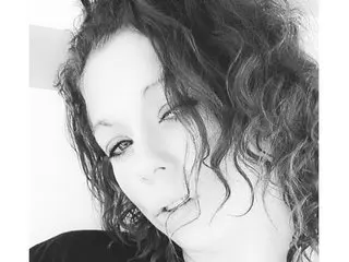 DivineMoonGoddess poses with her curly hair framing her face, looking directly at the camera with a slight smile.