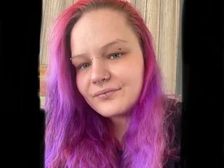 Divine_Attitude26 looks directly at the camera with long purple hair and a small nose piercing.