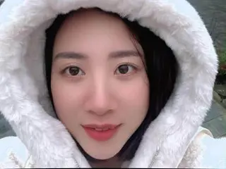 Smiling young woman in a cozy white faux fur hooded winter jacket outdoors.