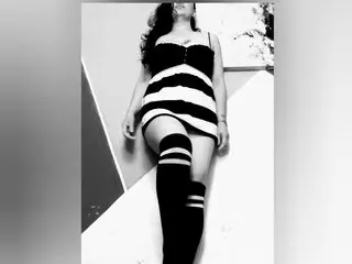 Woman in a striped mini dress and thigh-high socks posing in a minimalist indoor setting with a moody vibe.