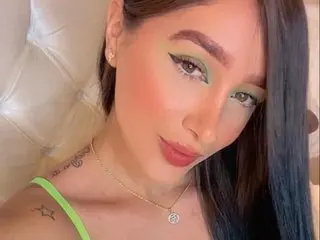 Young woman with green eyeshadow and a lime green top posing indoors with a soft, glamorous mood.