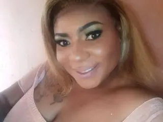 EbonyhotAss40 poses with a smile, showing her long blonde hair and light pink top against a plain background.