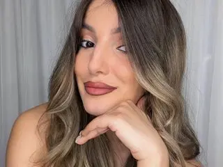 EllaHale poses with a soft smile, showing her long brown hair and face against a white curtain background.