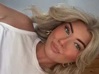 ElleWright poses with her blonde hair swept back, wearing a white tank top that shows her shoulders and neck.
