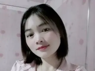 ElliBee has short black hair and looks directly at the camera with a soft smile in a close-up headshot.