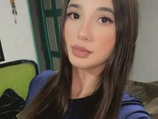 EmaDuvall looks into the camera with long brown hair and a blue top.