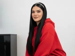 EmiilySquirtt with long black hair and a white headband wearing a red hoodie.