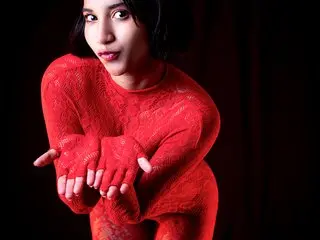 EmilyBruss poses in a red long-sleeve top, looking at the camera with dark hair against a black background.