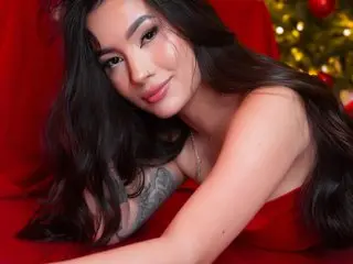 Smiling woman in a red dress relaxing near a glowing Christmas tree in a festive holiday mood.