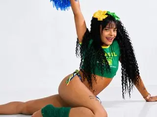 EmmaEbonyX19 poses with her long dark hair, wearing a green bikini top and matching bottoms against a white background.
