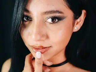 Emmawebbb poses close-up, showing her face, dark hair, and eyes with heavy black eyeliner.