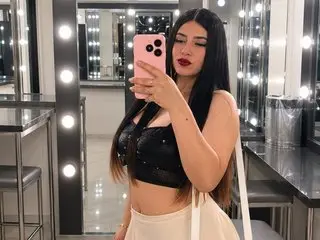 Young woman in a black crop top taking a selfie in a glamorous lighted makeup dressing room.