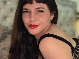 EvangeliineRoss poses with long dark hair and red lipstick, looking at the camera in a close-up shot.