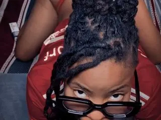 ExclusiveBarbii wearing black glasses and a red top while looking up at the camera.