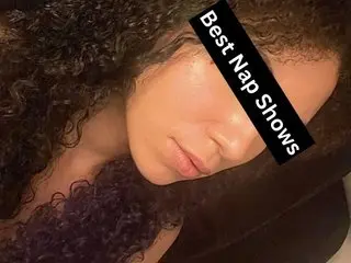 Young woman with curly hair relaxing in bed for a cozy nap time mood.
