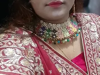 FairyBeauty1999 wears a red embroidered sari and a heavy, colorful jeweled necklace with red, green, and gold stones, showing her neck and shoulders.