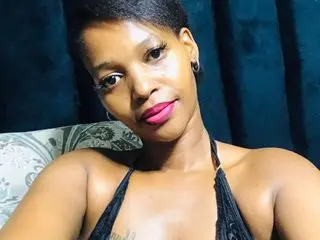 FancyFaceKay poses in a black halter top with short dark hair against a dark blue backdrop.