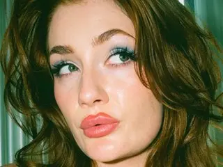FionaMinxxBabestation looks directly at the camera with a close-up headshot, showing her long brown hair and light eyes.